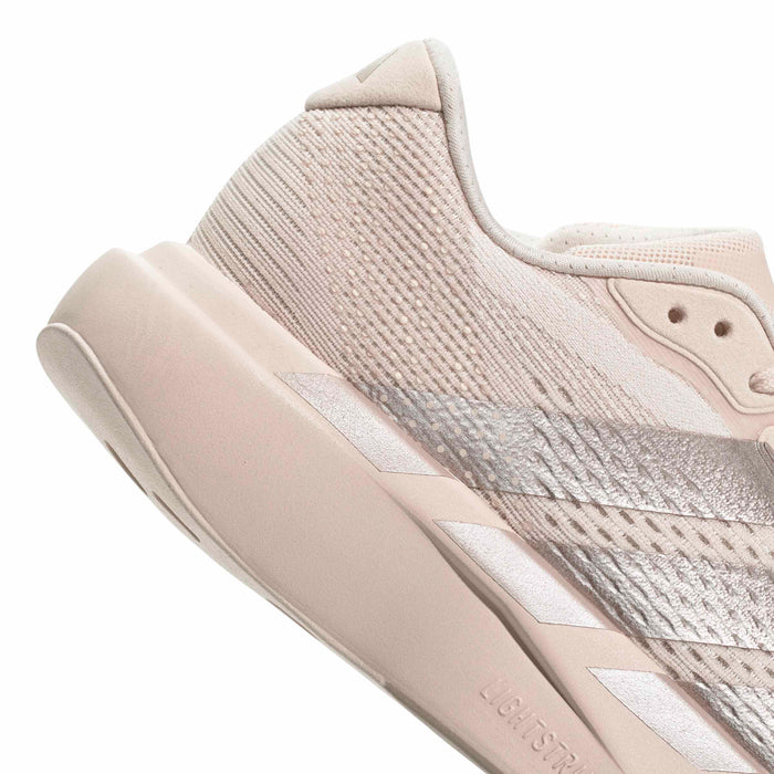 Women’s running shoe side profile in light pink with textured knit and cushioned midsole.