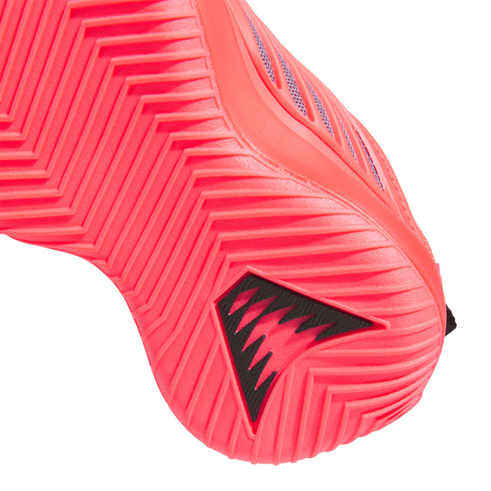 Kids sneaker outsole close-up, orange traction tread with black and dark logo mark.