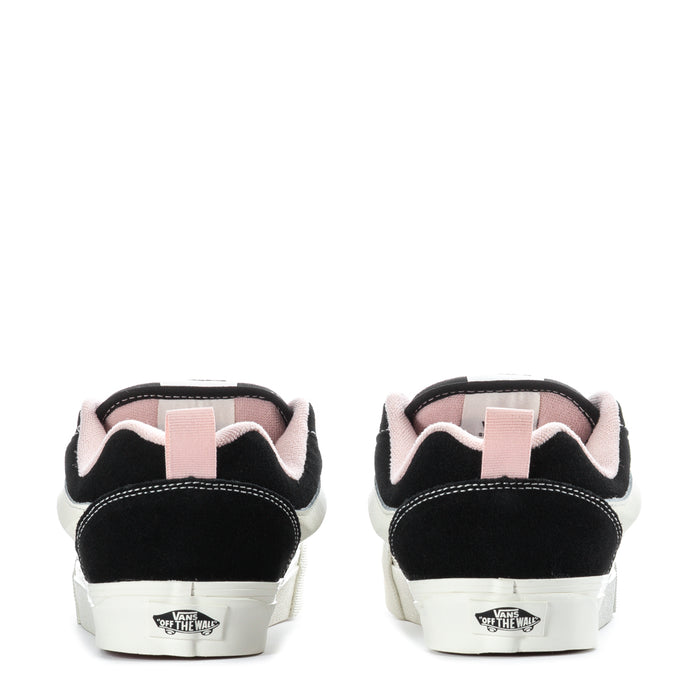 Black low-top sneakers with white rubber sole and pink heel lining, back view.
