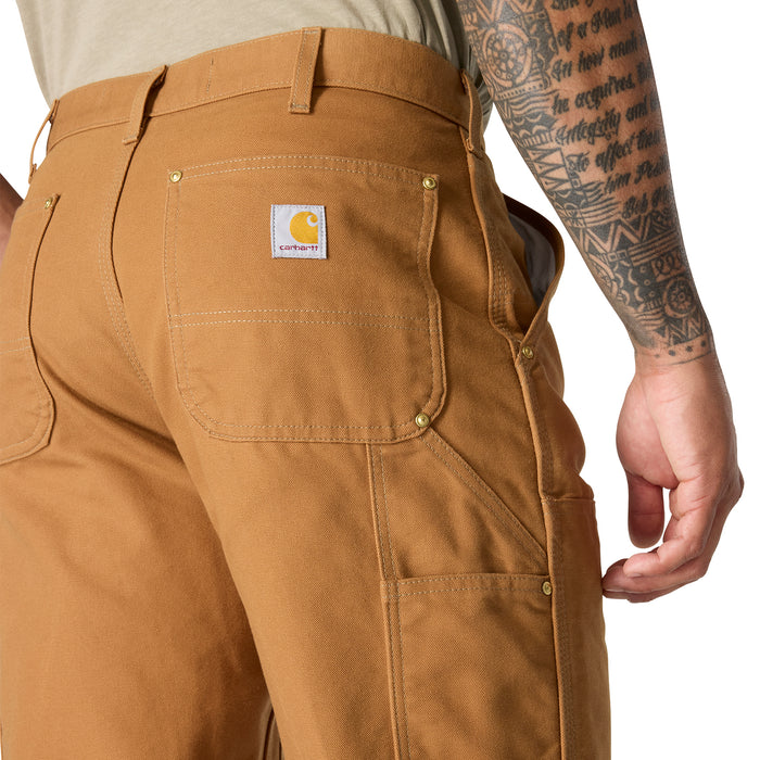 Brown dungaree pants close-up: back yoke, branded label, and double-stitch pockets