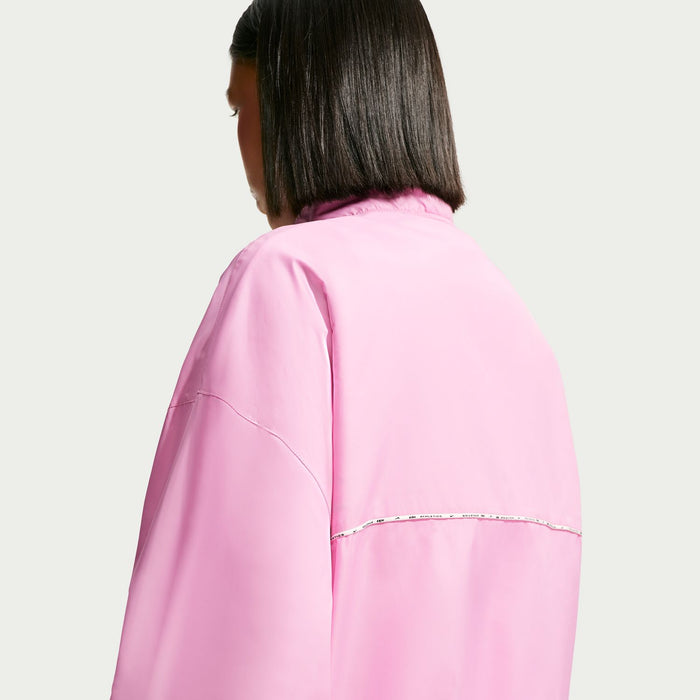 Women's pink windbreaker jacket back view with reflective seam piping across shoulders