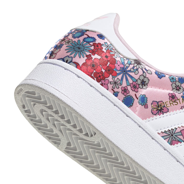 Youth sneaker toe close-up with pink floral upper and white rubber shell sole.