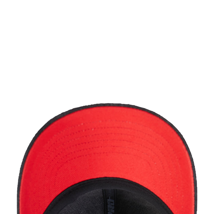 Red inner lining of a washed black strapback cap with black brim edge