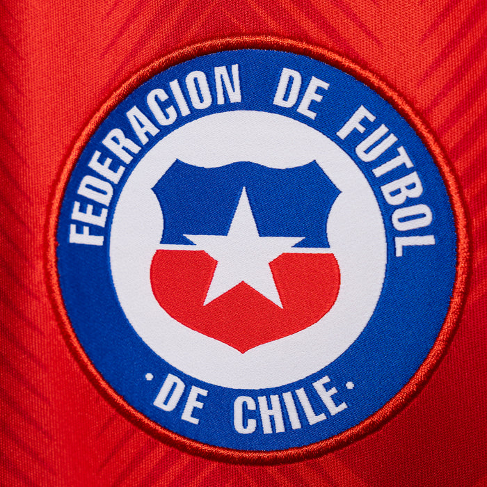 Team crest patch on red soccer jersey, blue circular emblem with white star
