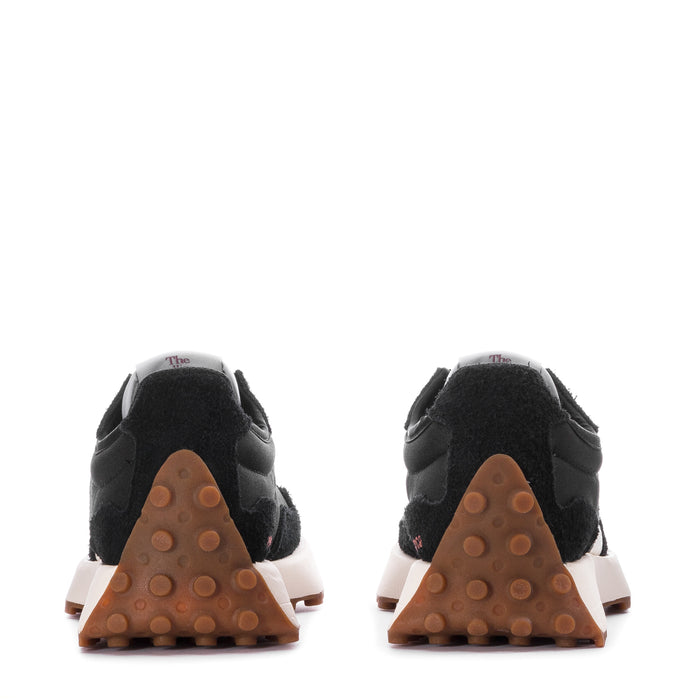 Women's black sneakers with white midsole trim and gum rubber heel tread.