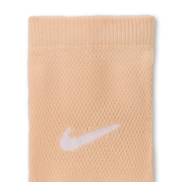 No-show sock fabric close-up in light peach with white swoosh logo
