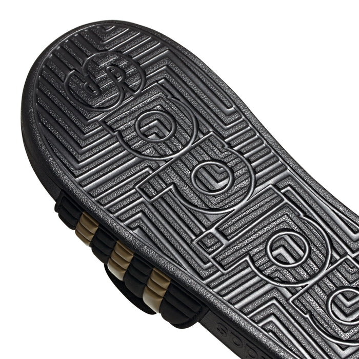 Men's black slide sandal outsole tread with adidas lettering and gold underlayer