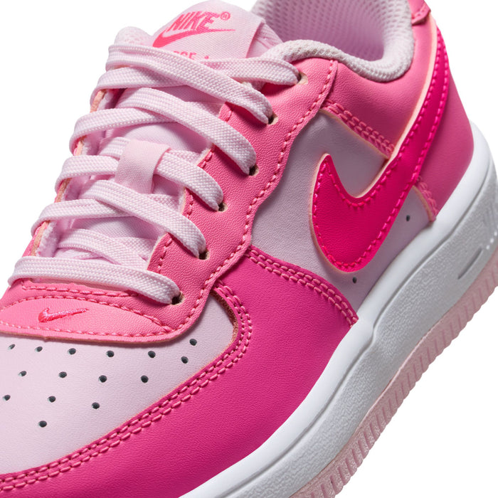 Kids pink Nike sneaker close-up of laces, white Swoosh, and perforated toe panel