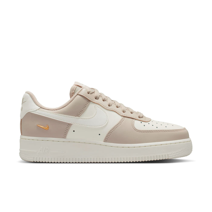 Cream and light tan low-top sneakers with lace-up front and gold Swoosh logo