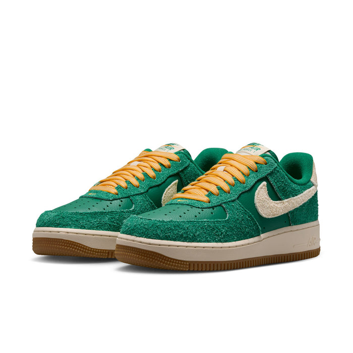 Pair of women’s green low-top sneakers with tan Swoosh, orange-yellow laces, gum sole