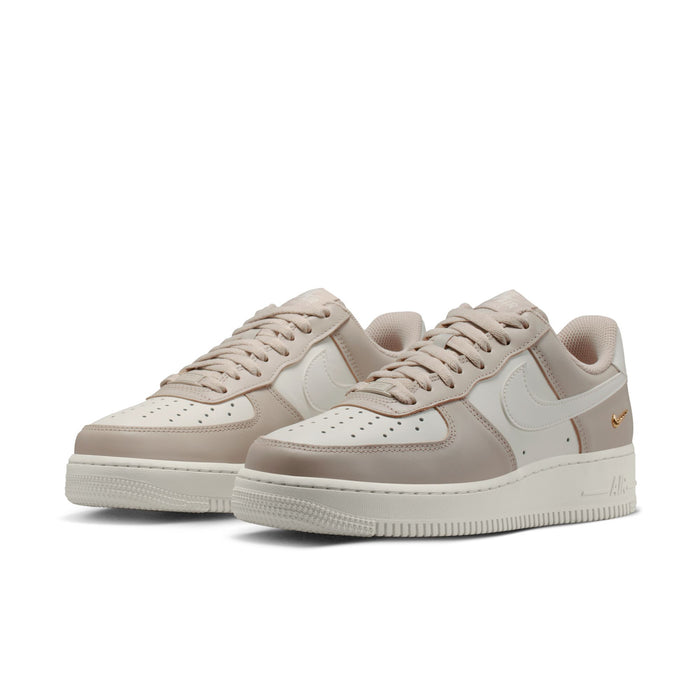 Light tan and cream low-top sneakers, side view, lace-up with gold Swoosh accent