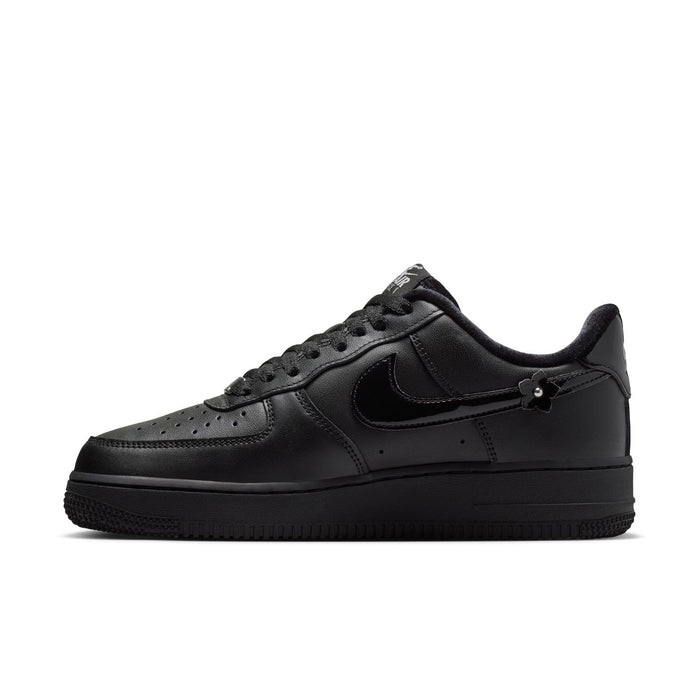 Women's black low-top sneaker, quarter-side view with Nike swoosh and studded appliques