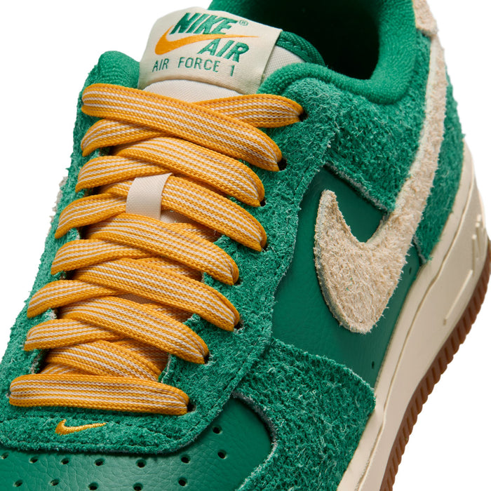 Close-up of green suede women’s sneakers with yellow-orange laces and Air Force 1 tongue