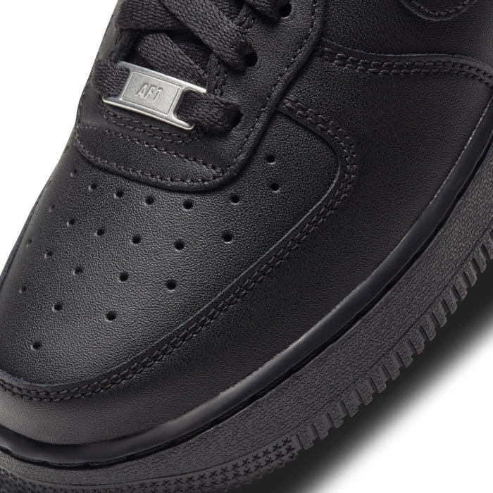 Black leather-look sneaker upper close-up, perforated toe and lace hardware