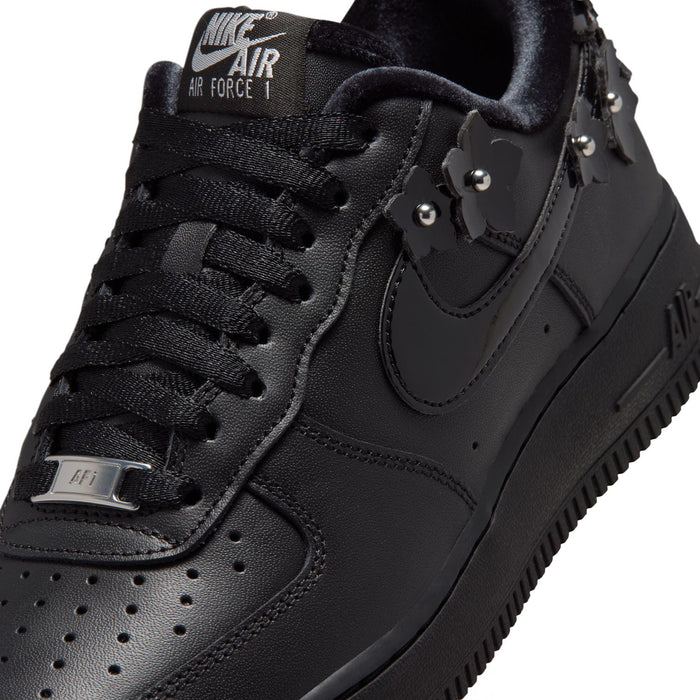 Women's black low-top sneaker close-up of laces and studded ankle charm details