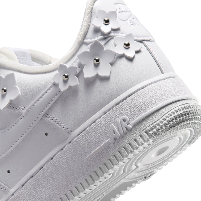 Close-up of white Nike Air Force 1 side with swoosh, metallic studs, and textured sole