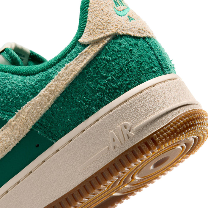 Side close-up of green suede sneaker with beige Swoosh and cushioned sole text detail