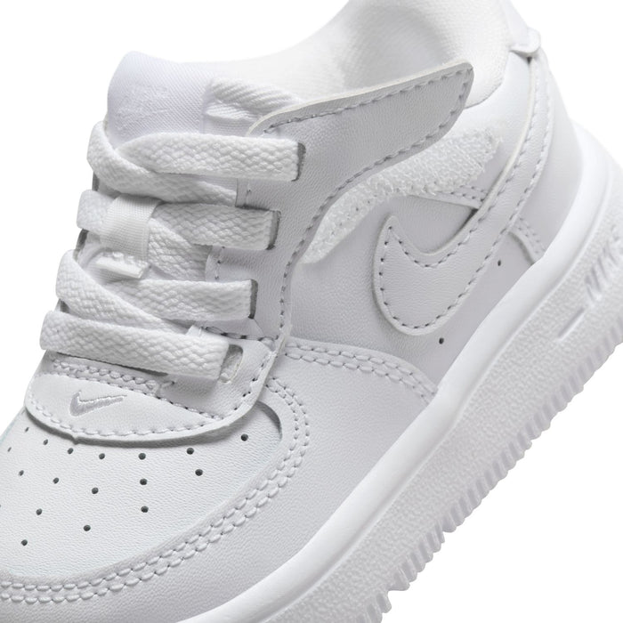 Toddler white low-top sneaker close-up with swoosh, laces, and textured midsole