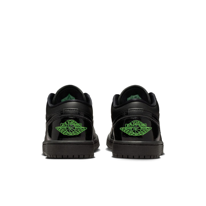 Black low-top sneakers with green heel logos and rubber outsole tread.
