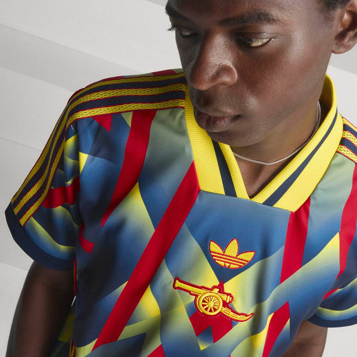 Close-up of men's multicolor jersey with yellow collar and crest logo at chest