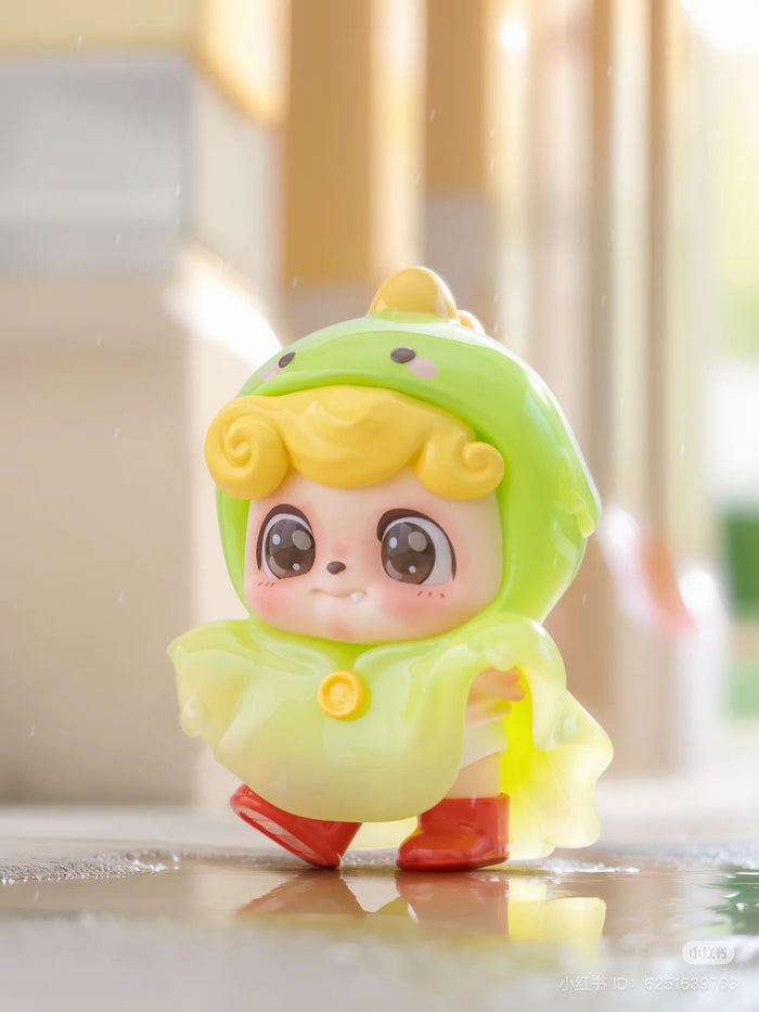 Be Your Q Baby Blind Box Series toy figurine in a raincoat, featuring a child-like cartoon face. Preorder for Aug 2024.