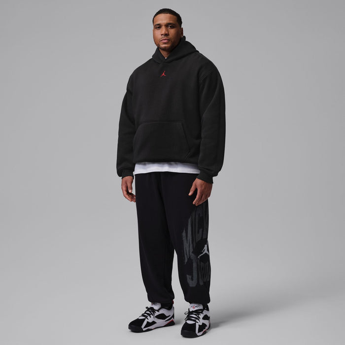 Men's black hoodie with hood and kangaroo pocket; model wearing matching black pants