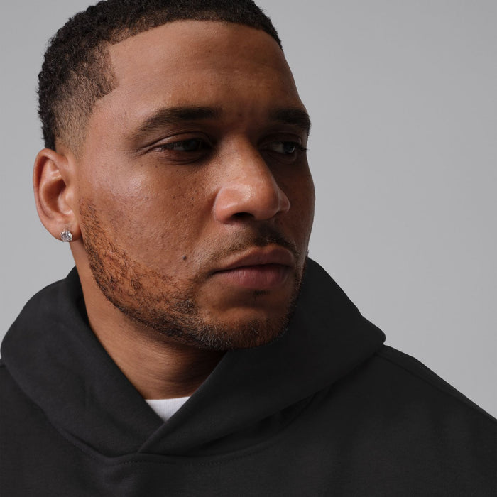 Men's black hoodie close-up on hood and shoulder; red Jumpman logo on chest