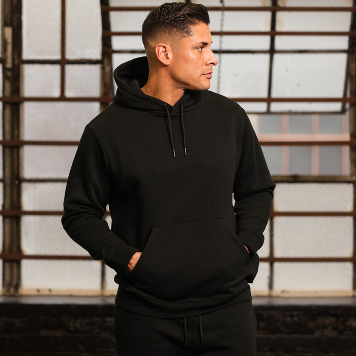 Black fleece pullover hoodie on model, with hood, drawstring, and front kangaroo pocket.