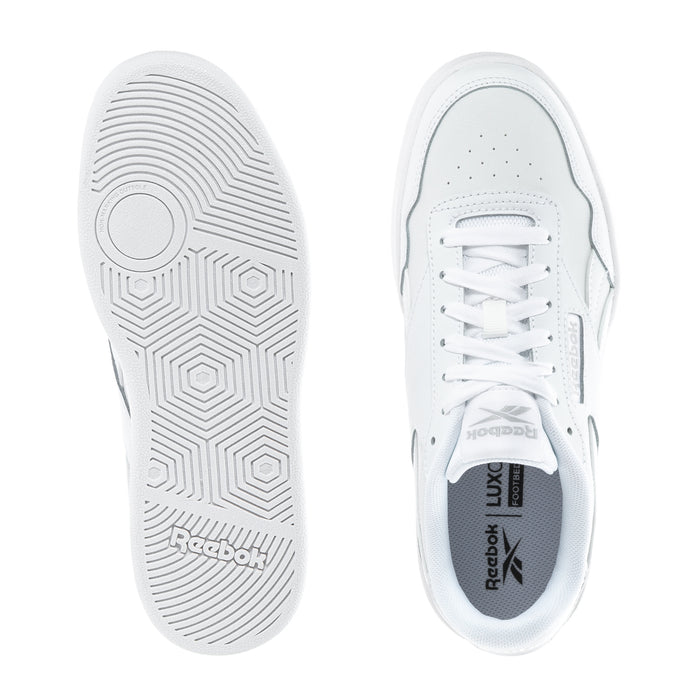 Women's white sneakers showing outsole tread and Reebok logo on inner tongue