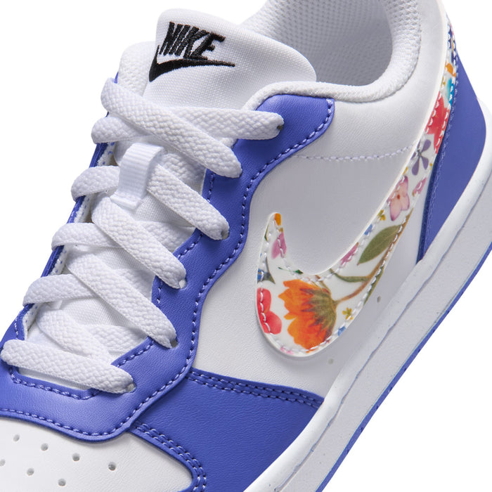 Close-up of youth sneaker upper: white laces, blue overlays, and graphic swoosh