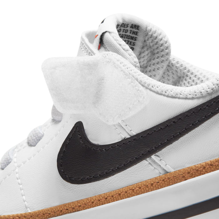 White toddler sneaker upper close-up with black NIKE swoosh and tan sidewall