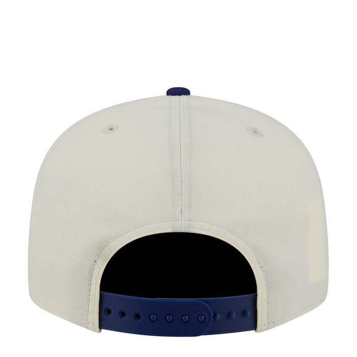 Two-tone baseball cap with cream crown and royal blue adjustable back strap.