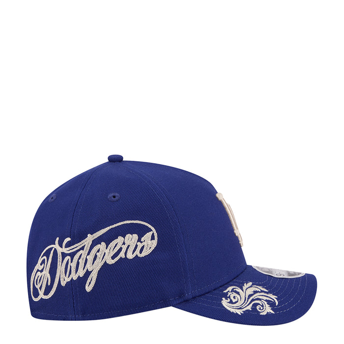 Blue baseball cap with large white Dodgers wordmark and ornate side panel embroidery