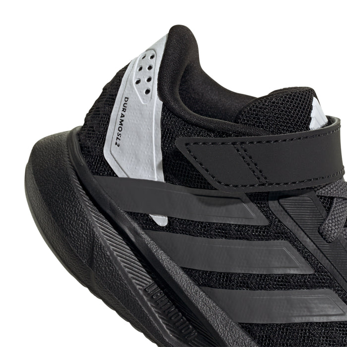 Kids black sneaker with white tongue label, hook-and-loop strap, and side stripe details