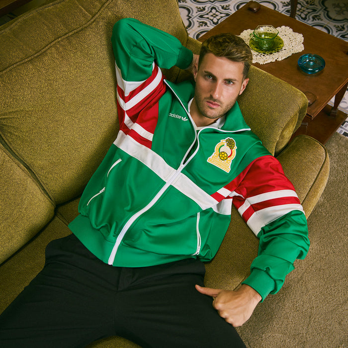 Green track jacket with red and white stripe panels, zip front, side pockets