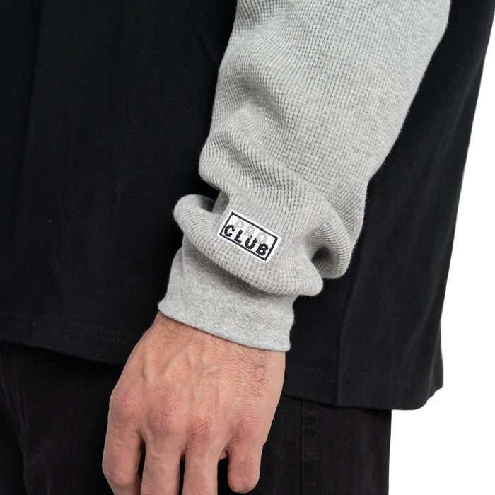 Ribbed heather grey cuffs with small logo patch on black thermal shirt