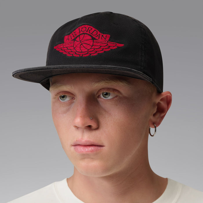 Black snapback cap with red Jordan wings emblem, worn front view.