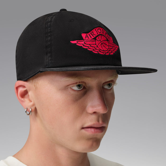 Black snapback cap with red Jordan wings emblem, profile view.