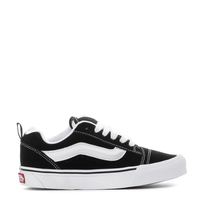 Black and white low-top sneakers with white stripe detailing and lace-up front
