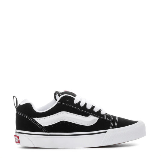 Black and white low-top sneakers with white stripe detailing and lace-up front