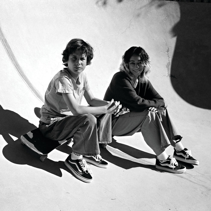 Pair of black and white low-top sneakers worn on feet, lace-up with white stripes