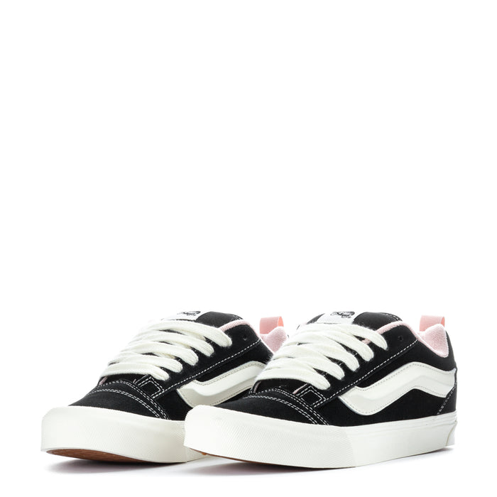 Pair of black low-top sneakers with white wavy stripe and white laces.