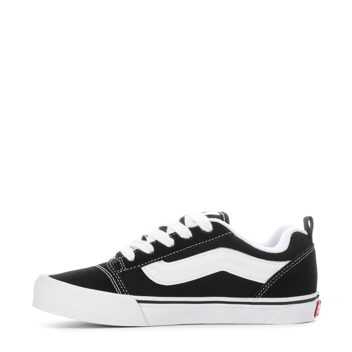 Black youth lace-up sneakers with white wavy side panel and chunky white sole.