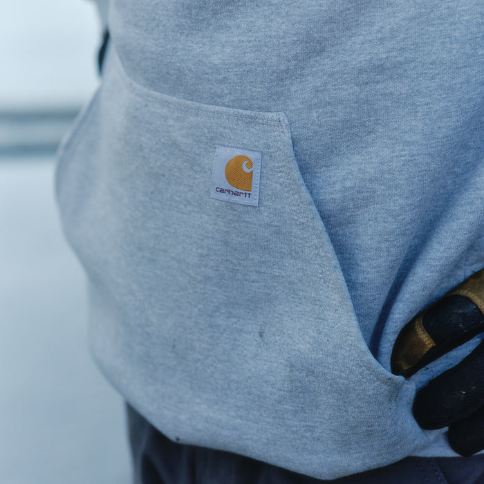 Heather gray hoodie pocket with Carhartt logo label detail near hem.