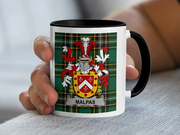 White mug with black handle, featuring Malpas family crest on plaid background.