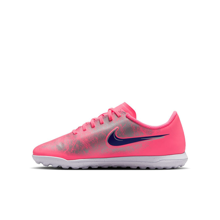 Youth pink turf soccer shoes with blue swoosh and textured, patterned upper