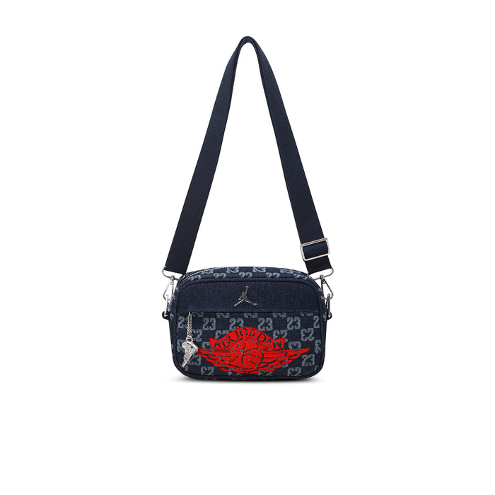 Dark indigo crossbody camera bag with adjustable strap and red logo graphic