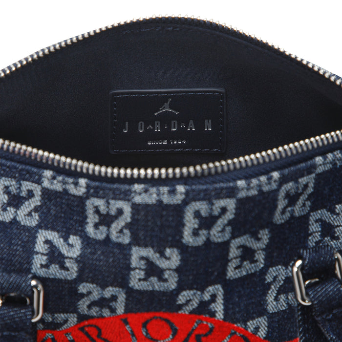 Close-up of dark indigo mini duffle bag interior pocket label and zipper trim