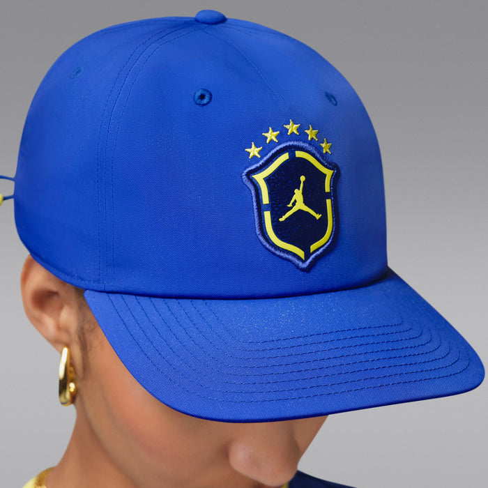 Royal blue snapback cap with yellow Jordan shield logo, angled side view