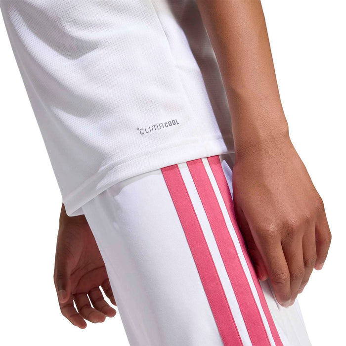 Youth white soccer jersey with teal armband and pink vertical shorts stripes